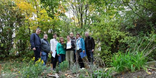 Gruppenbild: acht Personen. Eine Frau hält eine Urkunde in der Hand