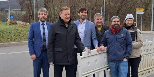 Sechs Personen stehen an einer geöffneten Absperrung.