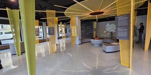 Blick in den Ausstellungsraum mit gelben Stelen und einem künstlichen Lagerfeuer.