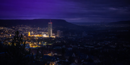 Panorama von Jena bei Nacht. Die eine Hälfte Jena ist dunkel.