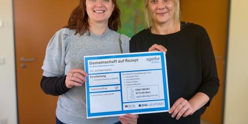 Zwei Frauen halten ein Rezept in die Kamera