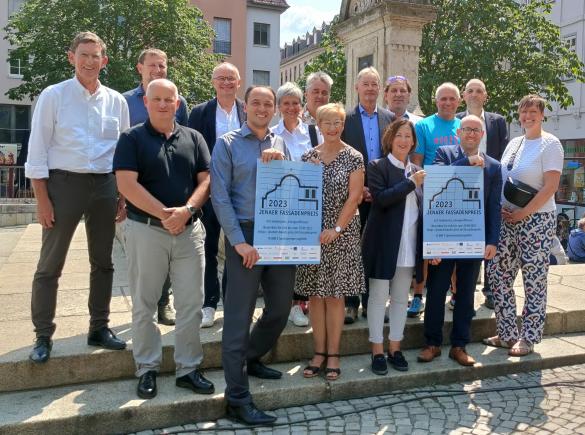 Bürgermeister Christian Gerlitz mit Sponsor*innen des Fassadenpreises stehen am Brunnen auf dem Marktplatz..