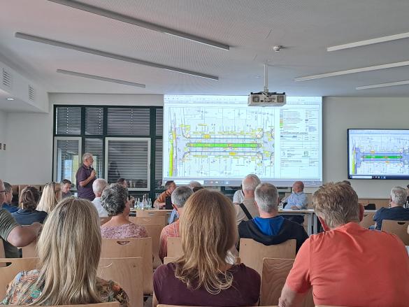 Menschen sitzen in einem Besprechungsraum und folgen einem Vortrag