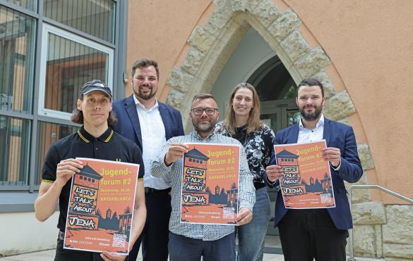 Fünf Personen halten drei Plakate in die Kamera.