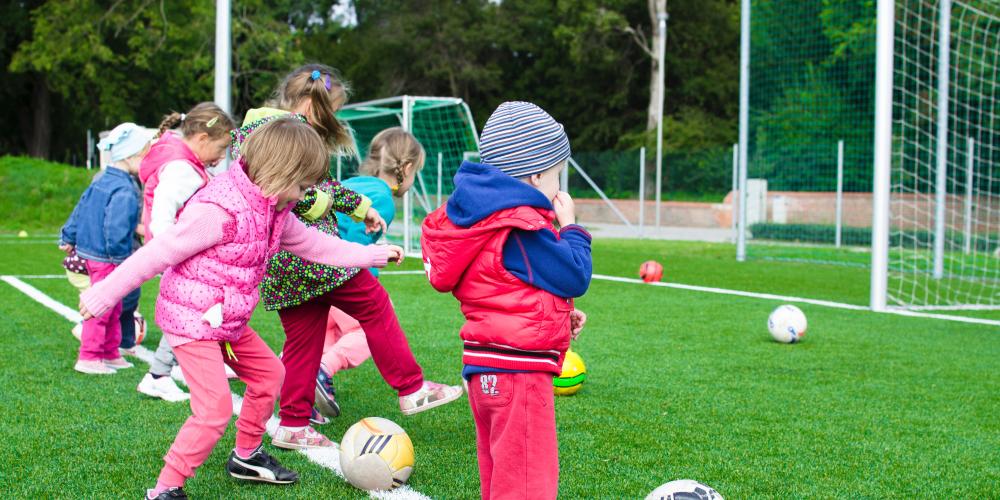 Kinder stehen vor einem Tor und schießen den Ball los