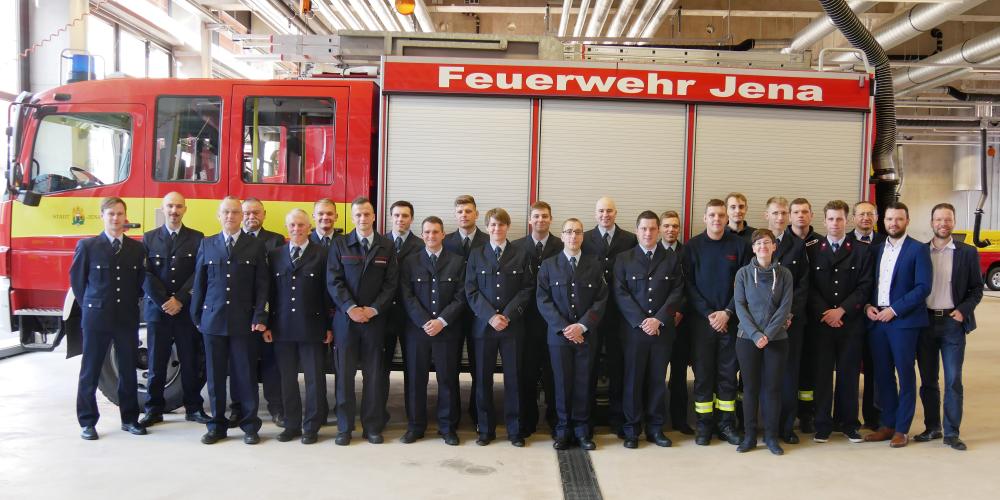 Eine Gruppe von Menschen in Uniformen vor einem Fahrzeug der Feuerwehr