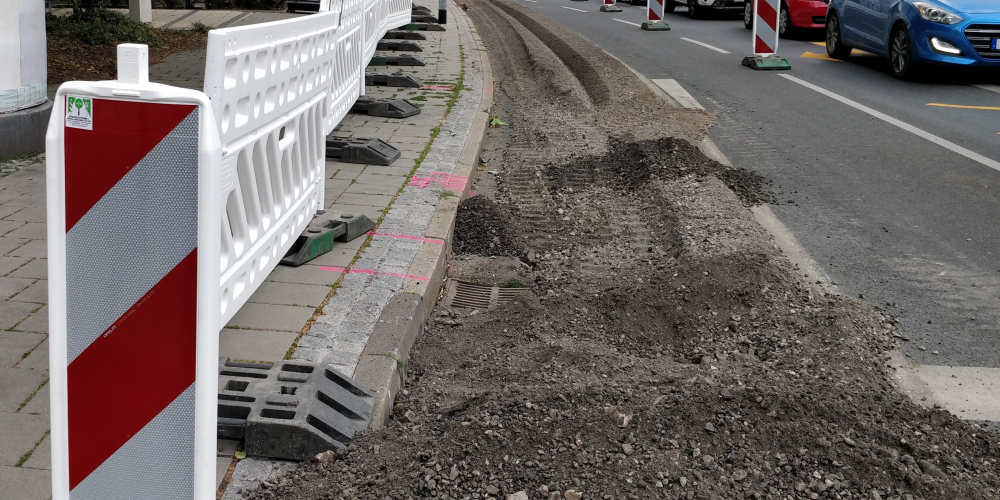 Der Abbeigestreifen einer mehrspurigen Straße ist wegen Bauarbeiten abgesperrt und der Asphalt aufgerissen. 