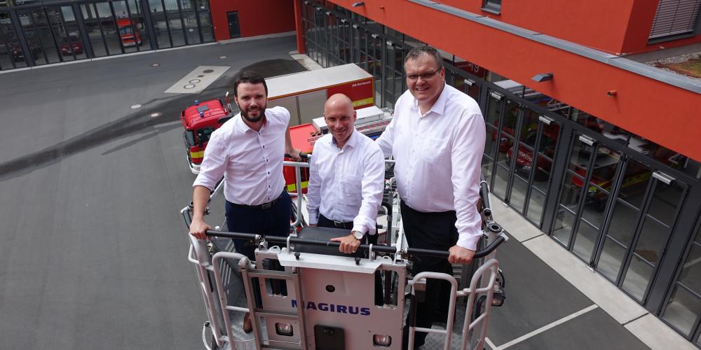 Die Dezernenten Koppe, Horn und Dannenberg (v.l.) stehen in einem Beöfrderungskorb einer Drehleiter. Die Drehleiter ist ausgefahren. Das GAZ und Feuerwehrautos sind im Hintergrund zu sehen. 