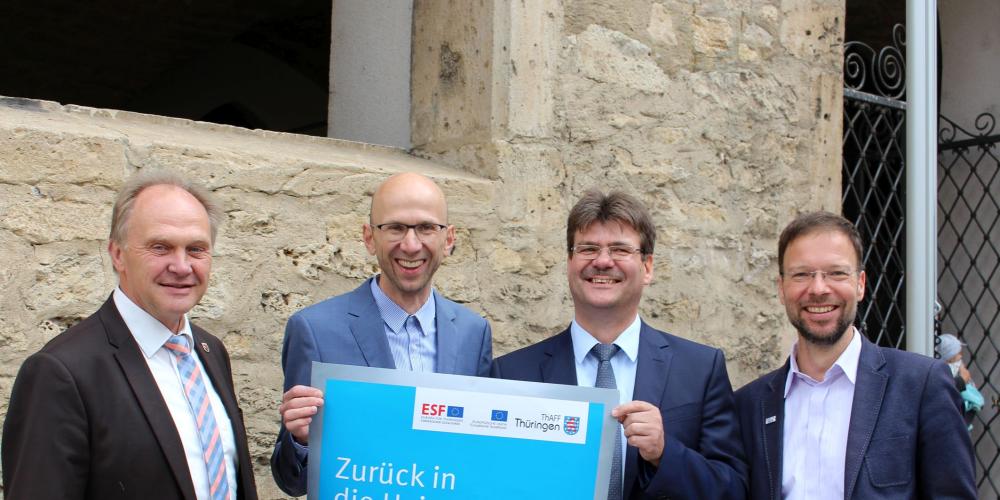 Andreas Heller (Landrat SHK), Wilfried Röpke (Wirtschaftsförderung Jena), Andreas Knuhr (Thüringer Agentur für Fachkräftegewinnung) und Dr. Thomas Nitzsche (Oberbürgermeister Jena) (v.l.n.r.) halten ein Plakat für den Pendlertag vor sich.