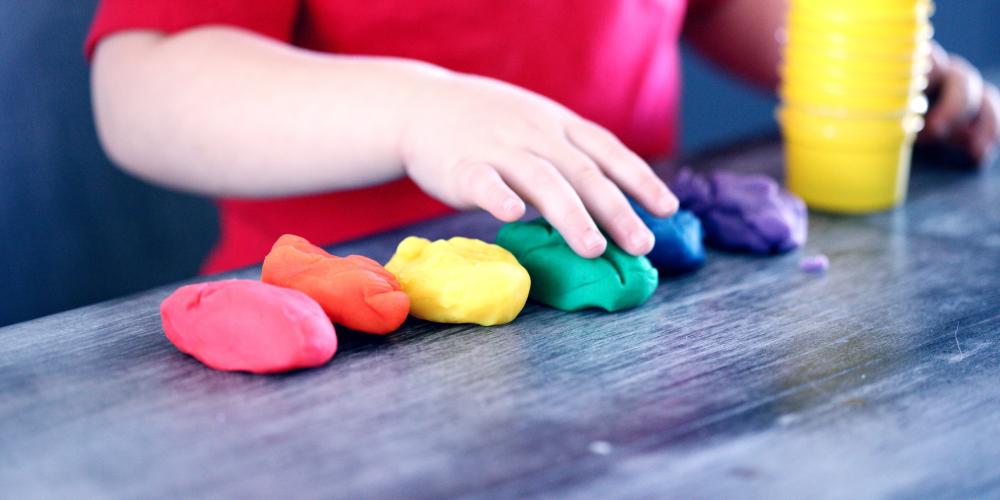 Kinderhand formt bunte Knete