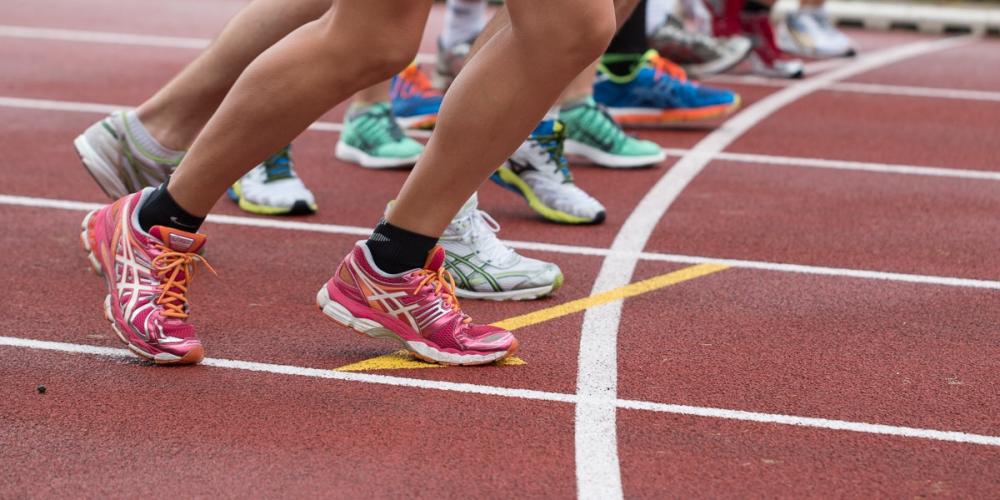Die Beine mehrere Läufer mit Turnschuhen und kurzen Laufhosen auf einer Laufbahn in Startposition