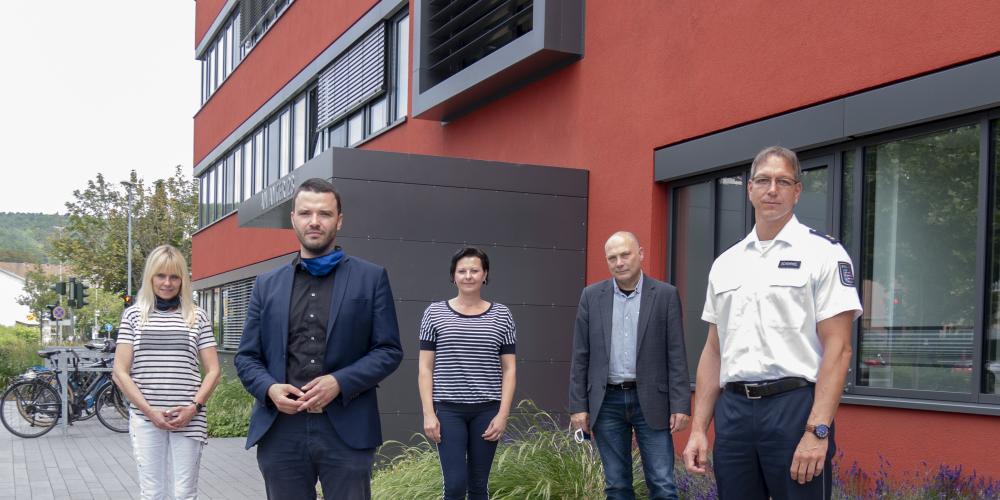 Fünf Menschen in einer Gruppe schauen in die Kamera