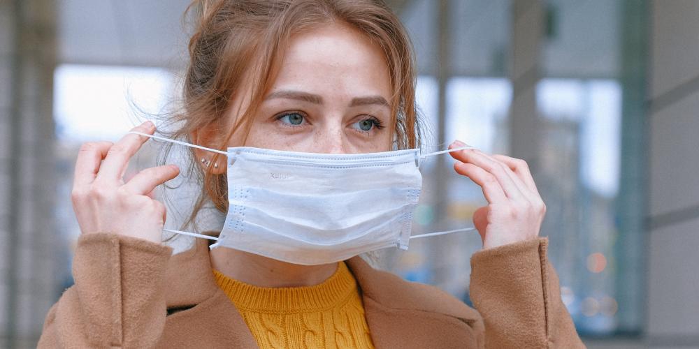 Eine Frau zieht eine Mund-Nase-Bedeckung auf. 