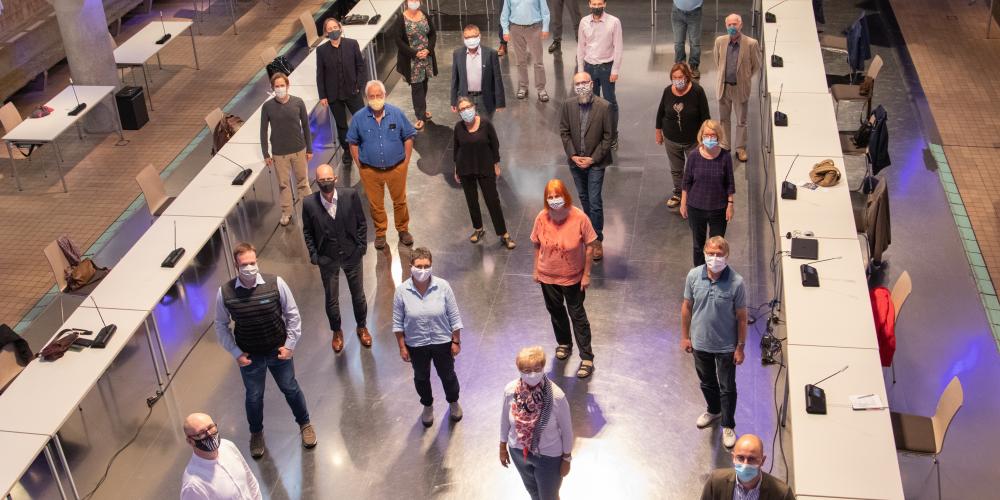 Viele Menschen in einem großen Raum, alle tragen Mund-Nasen-Bedeckung