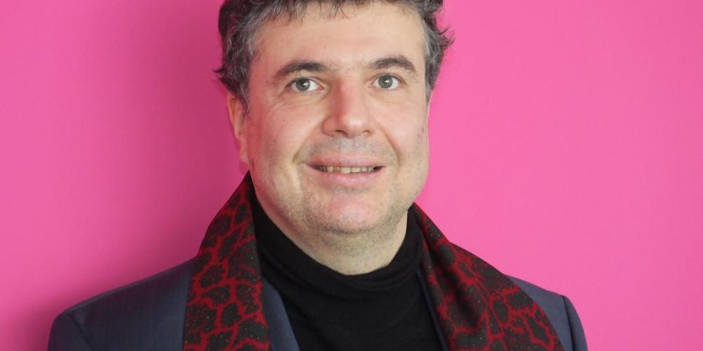 Ein Mann mit Künstlerschal schaut in die Kamera