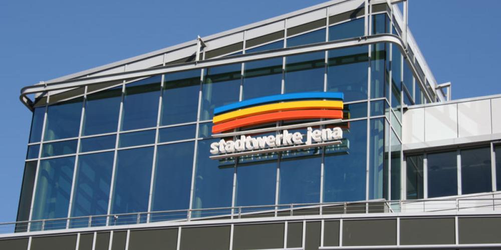 Blick auf eine Gebäudefassade mit viel Glas und Metall, im Hintergrund Himmel