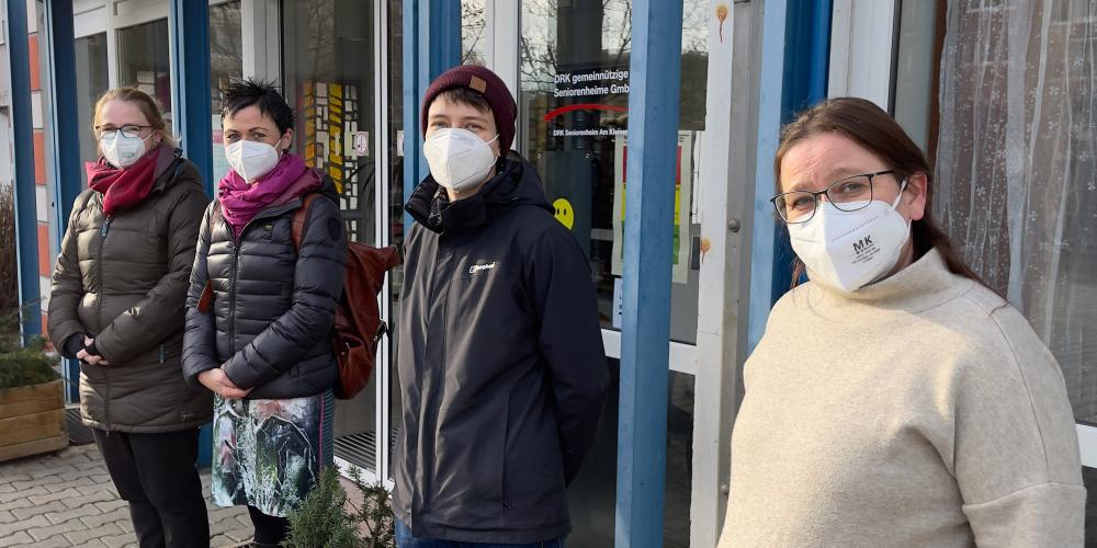 Vier Frauen mit Schutzmaske vor einem Altenheim