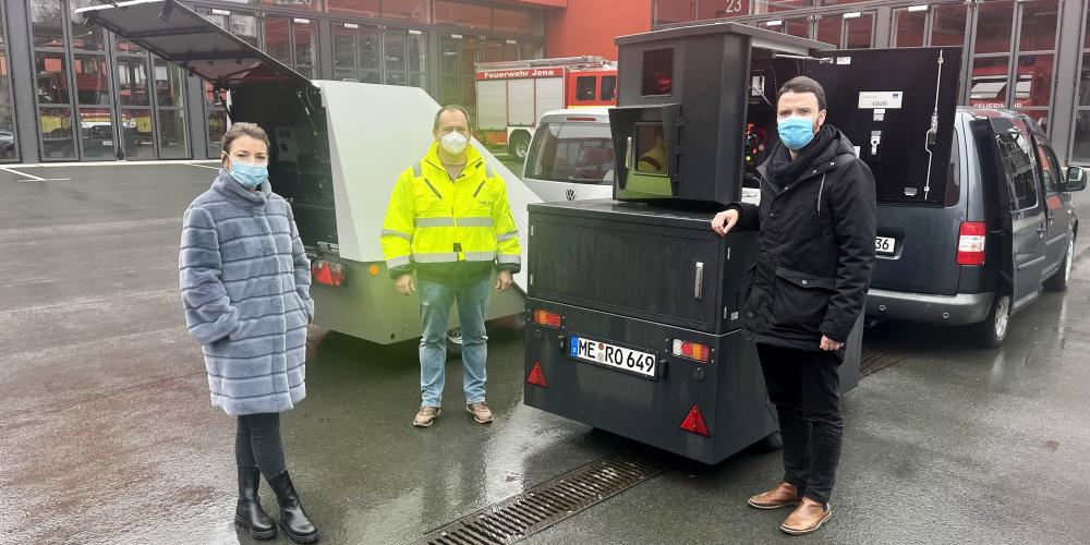 Drei Menschen mit Maske vor technischen Geräten