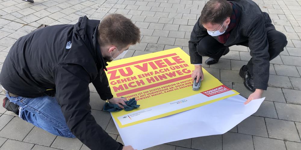 Zwei Menschen kleben einen Bodenaufkleber