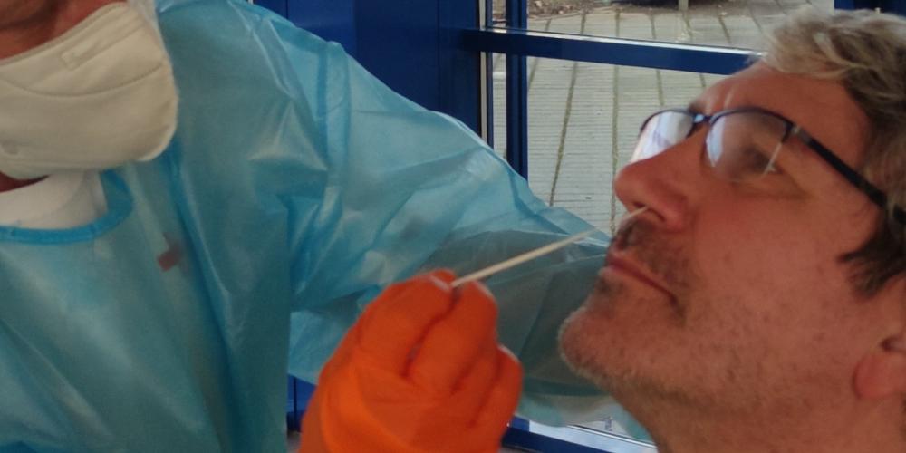 Ein Mann führt ein Stäbchen in die Nase seines Gegenübers