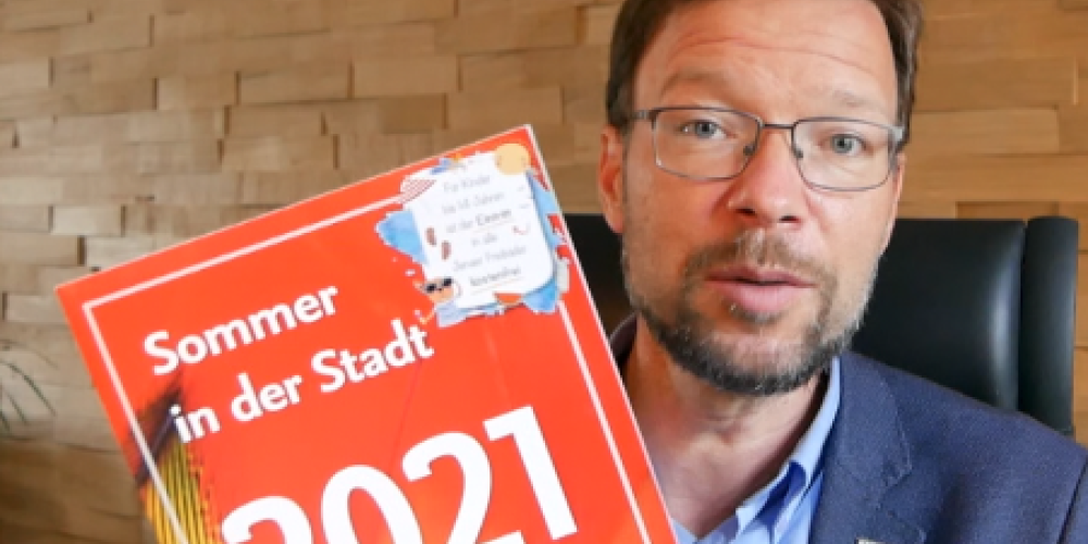 Ein Mann hält eine Broschüre in die Kamera