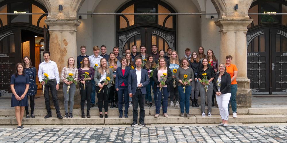 Eine große Anzahl an Personen steht im Außernbereich vor einem Gebäude