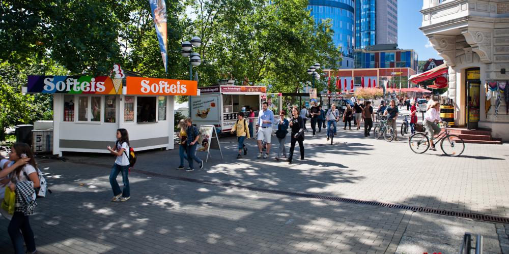 Blick in die Fußgängerzone Johannisstraße mit Fußgängern, Radfahrern und dem Jentower in Hintergrund.