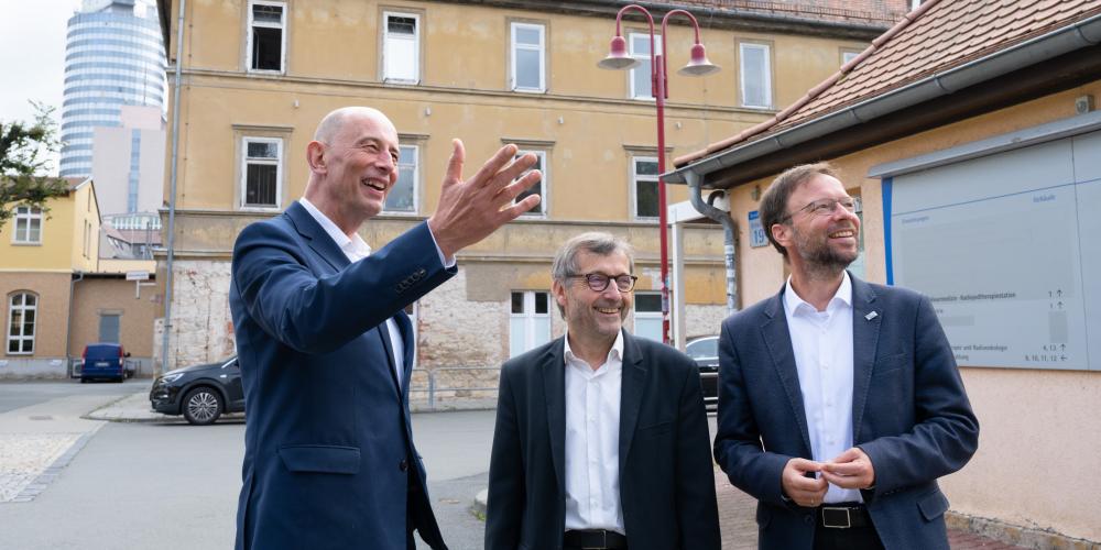 3 Männer im Außenbereich sehen sich etwas gemeinsam an.