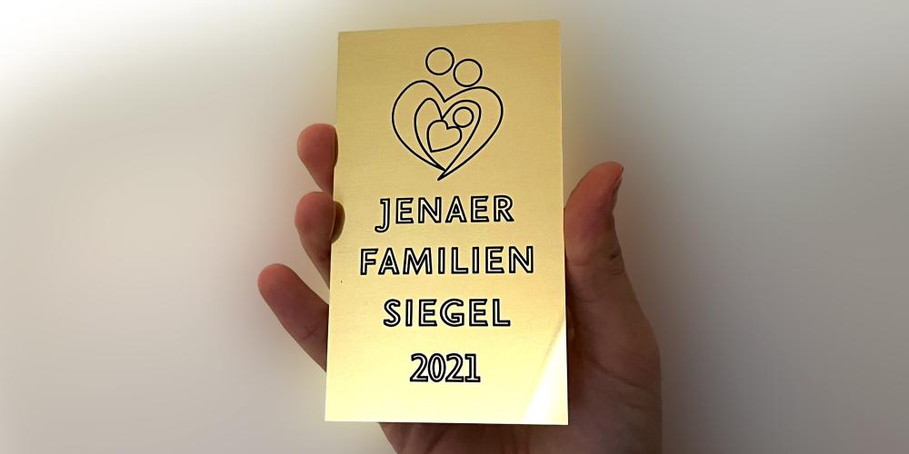 Eine Hand hält eine goldfarbene Tafel in die Kamera