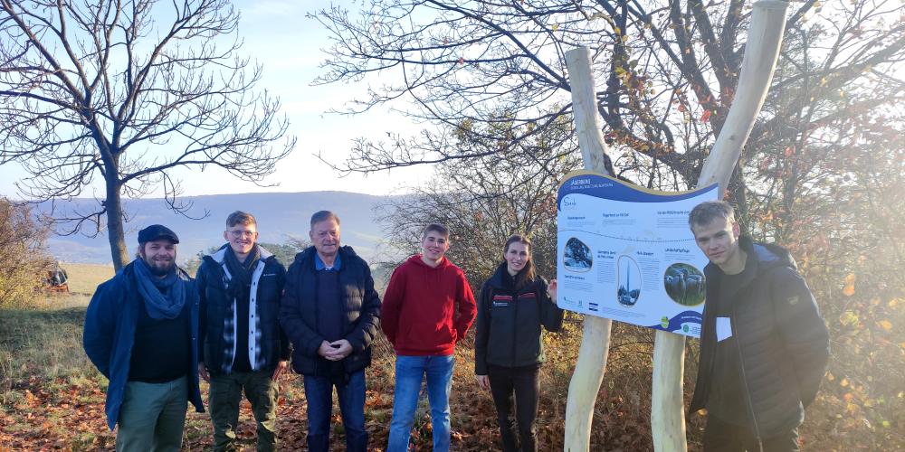 Menschen stehen in der freien Natur um eine Informationstafel
