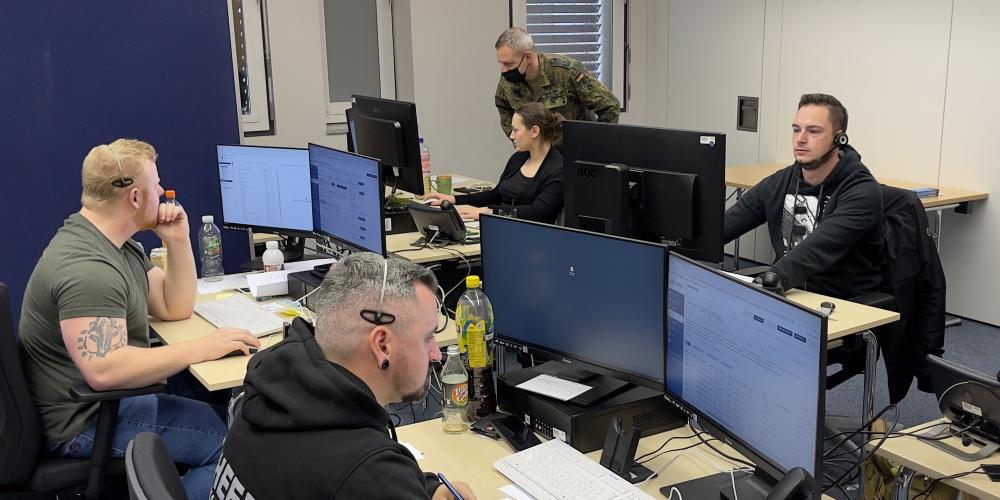 Vier Personen in einem Raum am Telefon