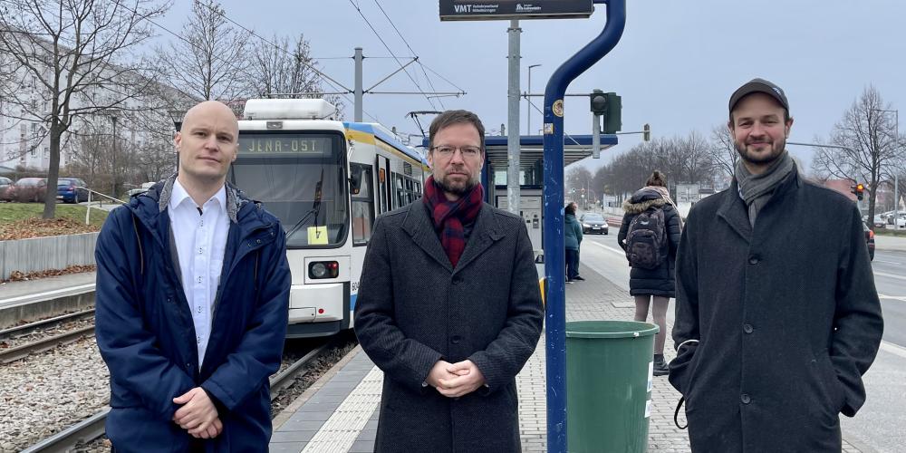Drei Männer an einer Haltestelle