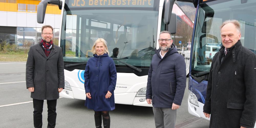 Vier Menschen vor zwei Bussen