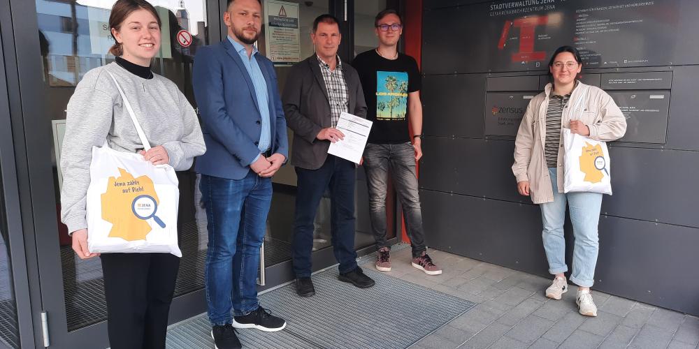 Mehrere Personen stehen vor  der Glastür eines Gebäudes