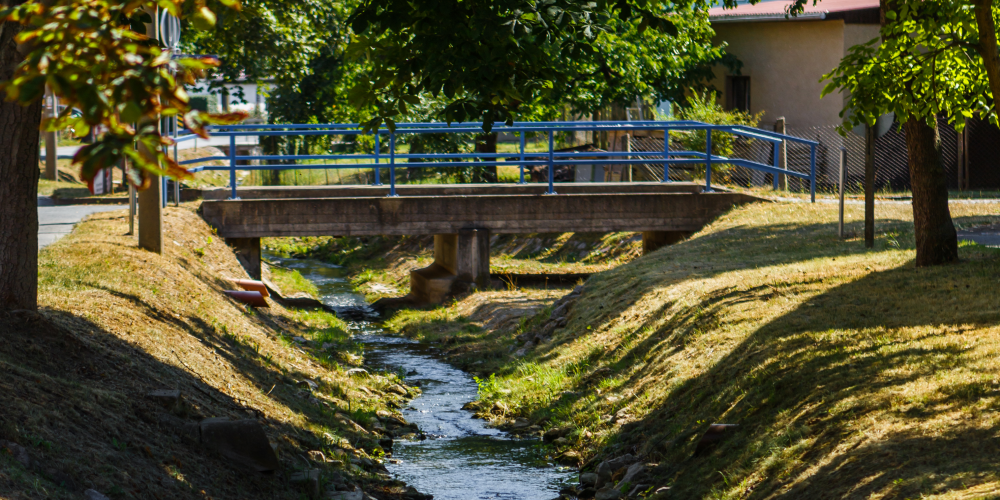 Ein Bach fließt unter einer Brücke entlang.