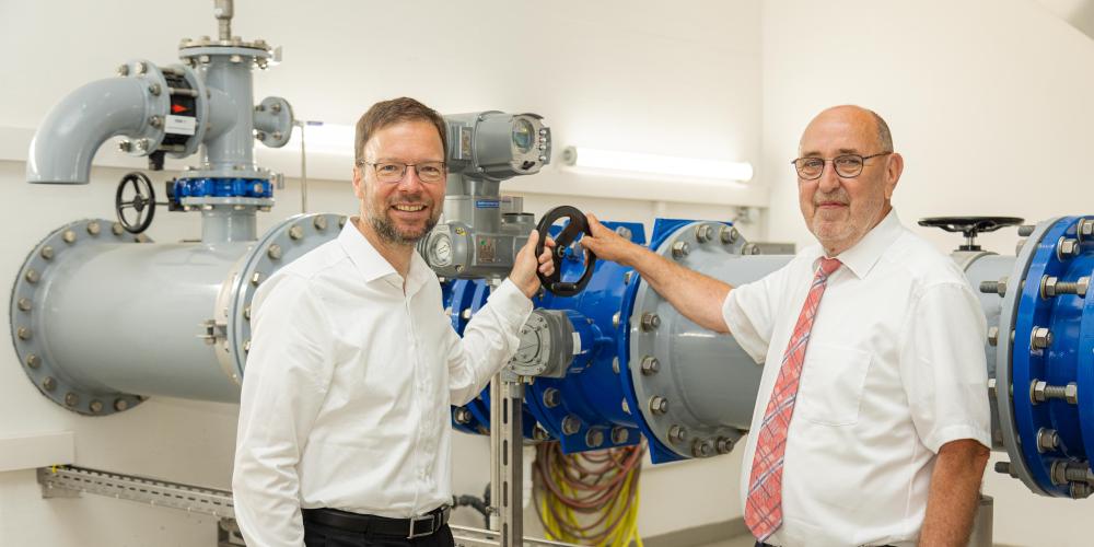 Zwei Männer vor großen Wasserrohren