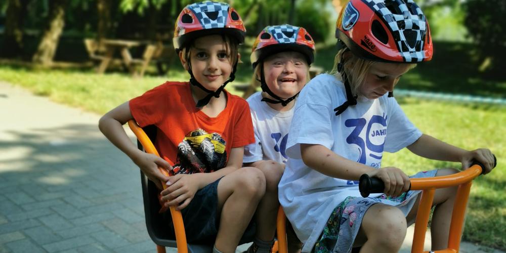 Drei Kinder auf einem Tretfahrzeug