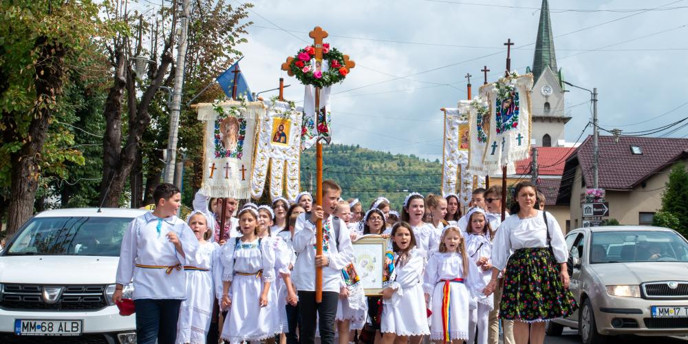 Bunt gekleidete Menschen bilden eine Prozession