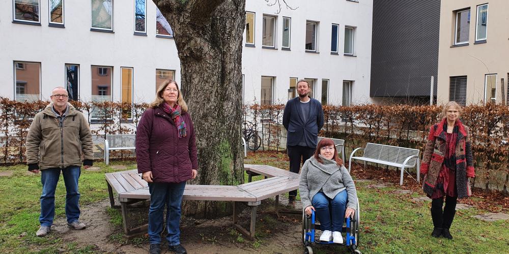 Auf dem Foto stehen im Freien mit Abstand nebeneinander 5 Personen: zwie Männer und drei Frauen