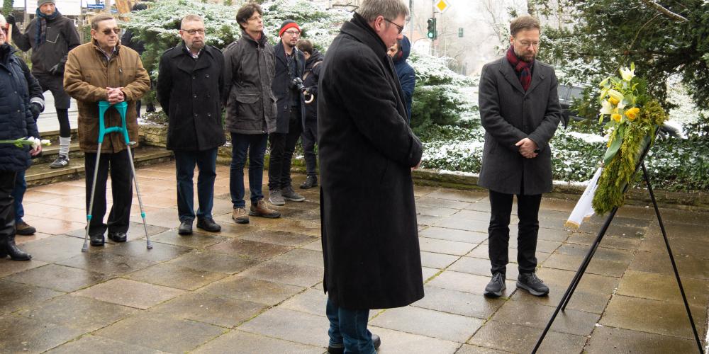 Menschen verharren vor einem Kranz