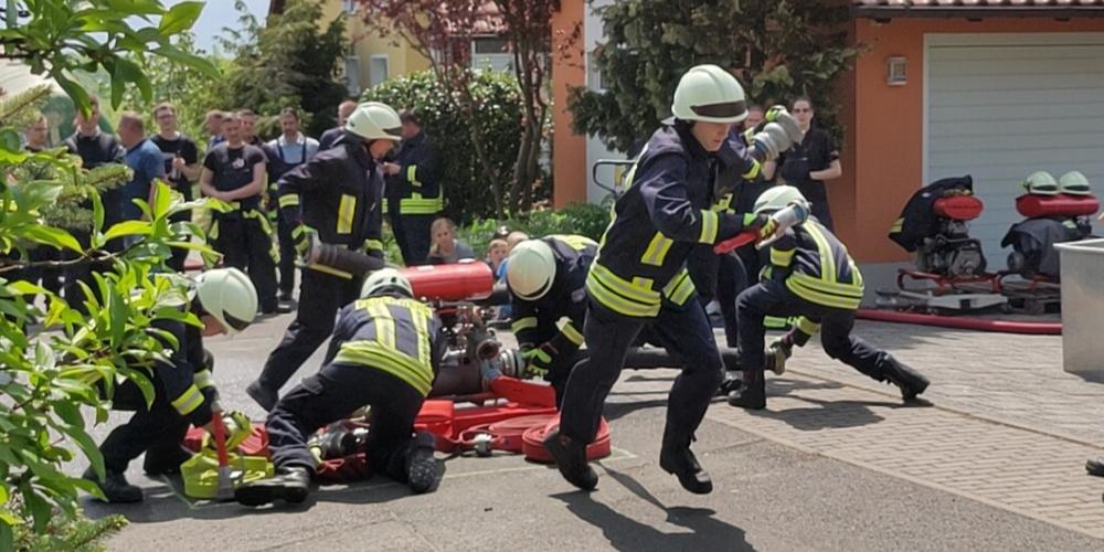 Feuerwehrmänner rennen mit Schläuchen in der Hand