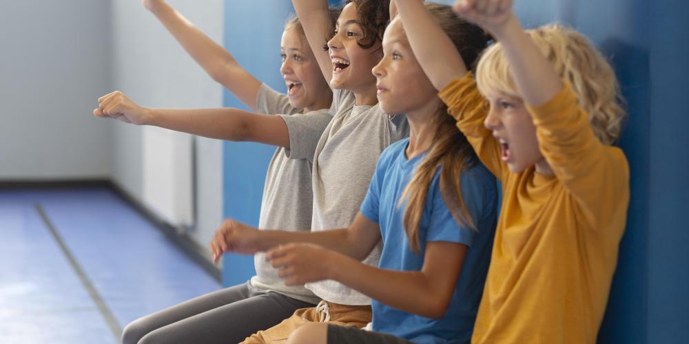 Kinder schauen begeistert vom Spielfeldrand zu.