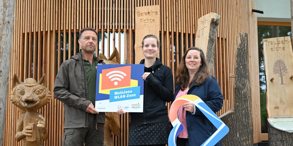 Stadtförster Olaf Schubert, Franziska Vogelsang vom Stadtforst und Christina Hentschel von den Stadtwerken  (v.l.) freuen sich, dass das Mein Jena-WLAN nun auch im Bereich des Naturerlebniszentrums am Schottplatz ausgestrahlt wird.
