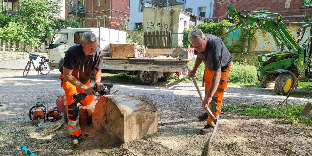 Zwei Männer stellen  große Scheiben eines Baumstammes zum Klettern auf.