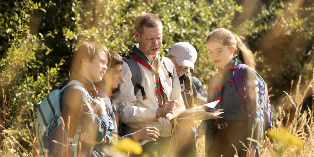 Vier Kinder und ein Mann bei einer Wanderung im Wald