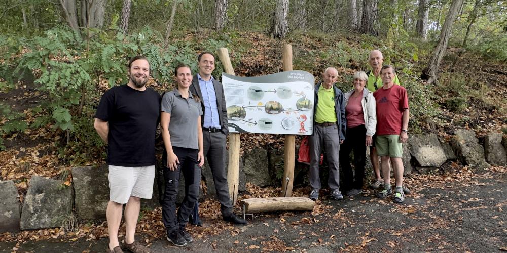 Menschen vor einer Informationstafel im Wald