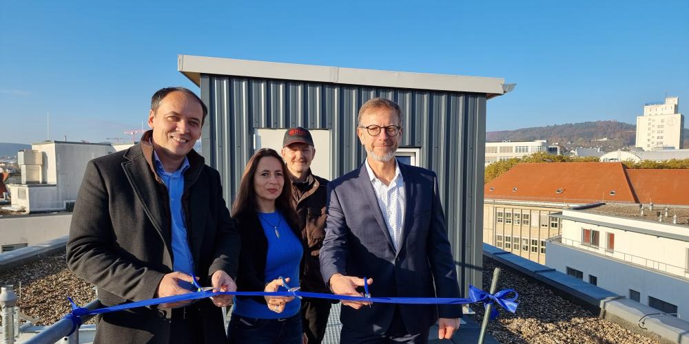 Bürgermeister Christian Gerlitz (v.l.), Kerstin Wuthenow (Ehrenamtliche Stadttaubenhilfe) und  Detlef Graba (Director Asset Management Technik und Nachhaltigkeit Real I.S. AG) schneiden ein Band vor dem neuen Taubenhaus durch. Hinter ihnen steht Taubenwart Torsten Schulz.