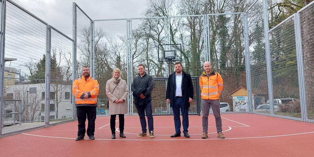 Fünf Personen stehen auf einem Bolzplatz.