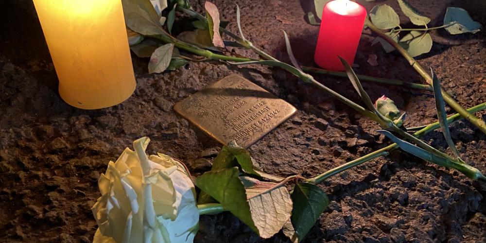 Blumen und Kerzen neben einem Stolperstein