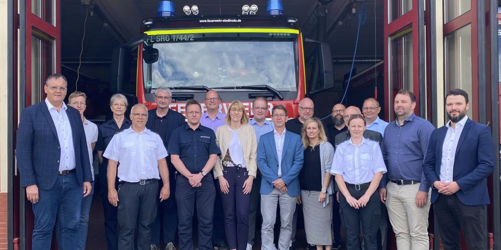 Viele Menschen stehen vor einer Feuerwache und schauen in die Kamera.